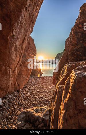 Plage cachée / Plage secrète au port de Vrbnik. belle petite baie entourée de falaises et d'une plage en pierre. Lever du soleil sur la mer Adriatique, île de Krk, Croatie Banque D'Images