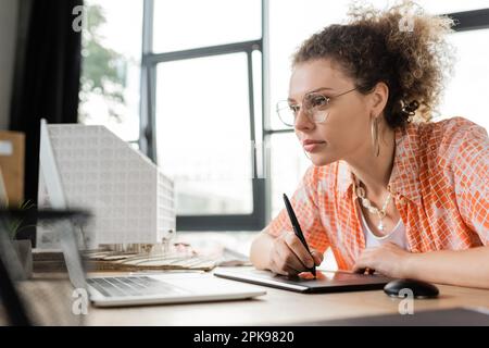 concepteur d'architecture spécialisé utilisant une tablette graphique et regardant un ordinateur portable tout en travaillant au bureau, image de stock Banque D'Images