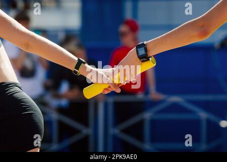 les femmes de main passent la course de relais de course de bâton en championnat d'athlétisme d'été Banque D'Images