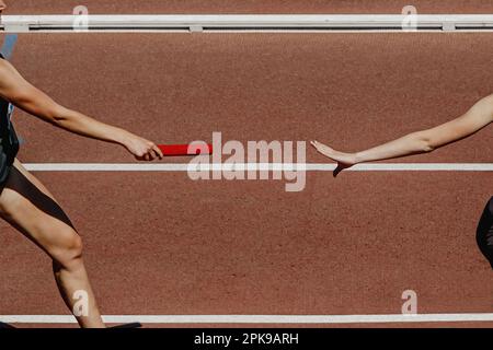 main femme coureur passant la course de relais de course de batton en compétition d'athlétisme d'été Banque D'Images