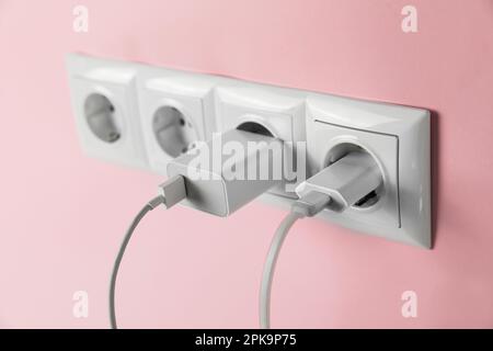 Adaptateurs de chargeur branchés sur les prises d'alimentation du mur rose, en gros plan. Alimentation électrique Banque D'Images