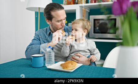 Le père et le fils sont assis sur une table pour prendre le petit déjeuner dans la salle à manger Banque D'Images