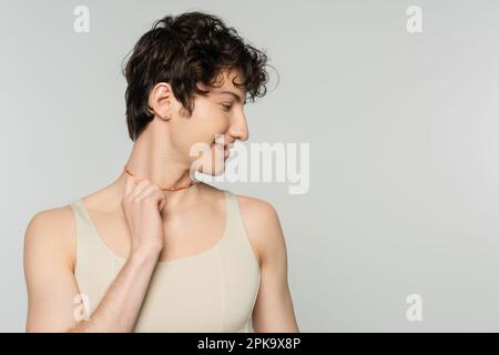 profil de curly bigender modèle dans le dessus de réservoir touchant les perles colorées isolées sur gris, image de stock Banque D'Images