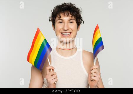 surjoyeuse personne non binaire dans des perles colorées tenant de petits drapeaux lgbt isolés sur gris, image de stock Banque D'Images