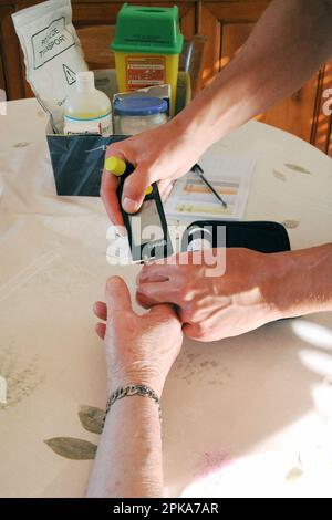 Infirmière de pays libéral au domicile d'un patient diabétique pour le test de glycémie et l'injection d'insuline. Banque D'Images