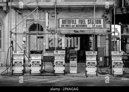 Une station-service avec une variété de pompes et des affiches de style vintage annonçant des produits de carburant. Banque D'Images