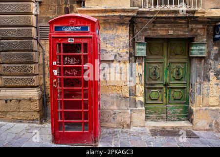 Un téléphone rouge classique devant un ancien bâtiment. Banque D'Images