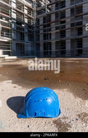 Le casque bleu pour ouvriers de construction se trouve sur le sol du chantier de construction abandonné Banque D'Images