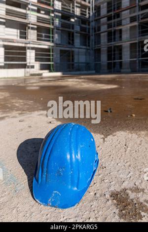 Le casque bleu pour ouvriers de construction se trouve sur le sol du chantier de construction abandonné Banque D'Images