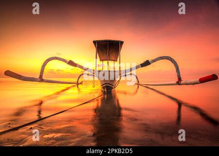 Bateau de pêche traditionnel Jukung au coucher du soleil de rêve sur la plage et la mer de Sanur, Denpasar, Bali, Indonésie Banque D'Images