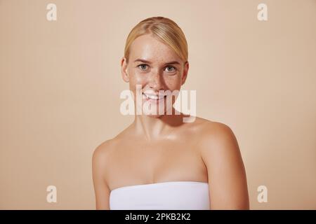 Jeune femme souriante avec des taches de rousseur regardant la caméra. Belle femme aux cheveux blonds et à la peau parfaite. Banque D'Images