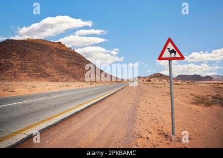 Route désertique vide à Wadi Rum, triangle rouge avertissement Camels près Banque D'Images