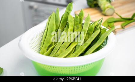 Légumes verts, haricots romano helda sur le disque à salade de légumes et brocoli sur le panneau de bois. Table de cuisine blanche à la maison. Le concept Banque D'Images