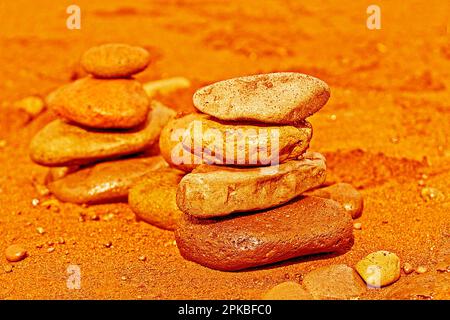 pierres empilées équilibrées ou cailloux sur sable volcanique noir en orange Banque D'Images
