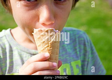 garçon mangeant de la glace dans une tasse de gaufres dans la nature Banque D'Images