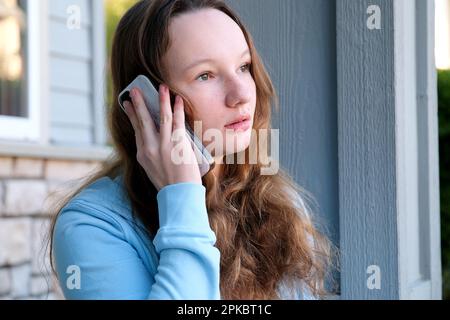 Une jeune femme moderne dans une chemise rose vif et des lunettes de soleil stylées parle au téléphone à l'extérieur lors d'une journée ensoleillée et sourira joyeusement l'expression calme de beau visage mignon de jeune fille adolescente parlant Banque D'Images