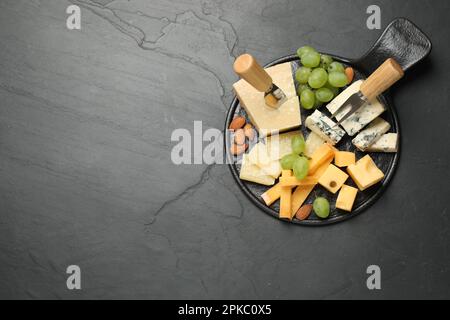 Plateau de fromages avec couteau spécialisé et fourchette sur table noire, vue de dessus. Espace pour le texte Banque D'Images