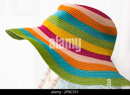 Chapeau d'été multicolore en paille sur fond blanc. Chapeau élégant avec larges marges. Femmes plage, chapeau coloré à rayures. Chapeau de paille élégant pour W Banque D'Images