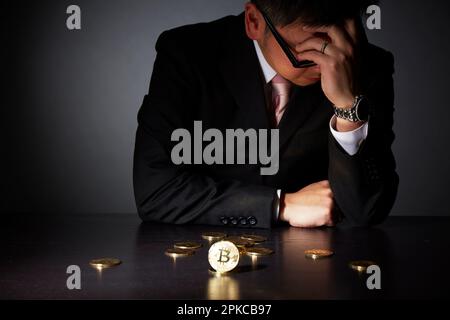 Homme en costume avec la tête tenu après un échec d'affaires avec bitcoin Banque D'Images