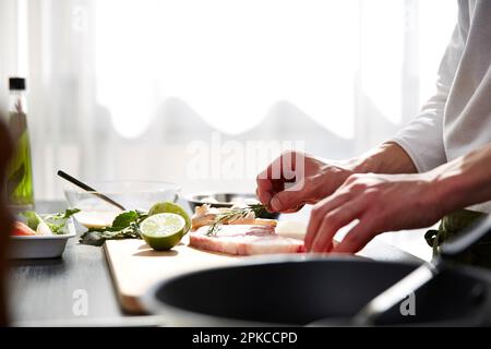 Main de l'homme appliquant l'assaisonnement à la viande crue Banque D'Images