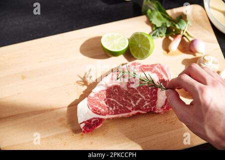 Assaisonnement des mains de l'homme à la viande crue Banque D'Images