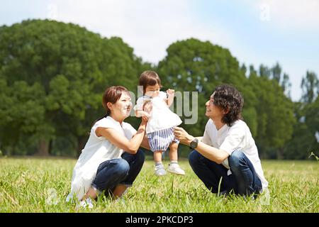 Bébé et parents jouant sur l'herbe dans le parc Banque D'Images