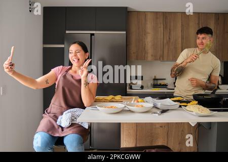 Deux jeunes latino prennent un selfie avec le téléphone tout en cuisinant. Banque D'Images