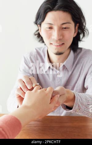 Un homme qui met un anneau d'engagement et la main d'une femme qui le reçoit Banque D'Images