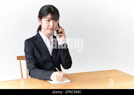 Une femme chasseur d'emplois qui écrit des notes au téléphone Banque D'Images