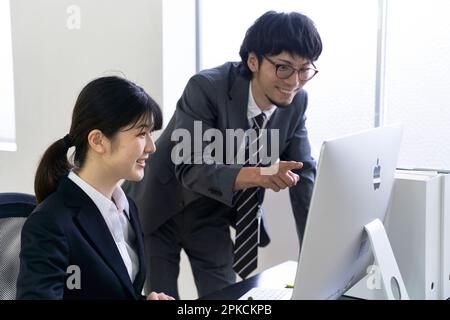 Une nouvelle employée qui utilise un ordinateur tout en étant enseignée à son travail par son superviseur Banque D'Images