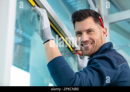 le constructeur mesure la fenêtre à l'aide d'un ruban de mesure sur le chantier de construction Banque D'Images