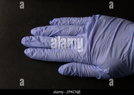 mains dans des gants médicaux sur fond noir Banque D'Images