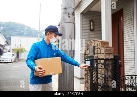 Homme d'accouchement portant un masque de sonnerie interphone Banque D'Images