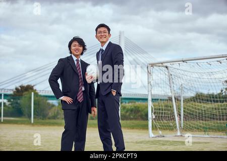 Deux employés de bureau portant un ballon de football sur un lit de rivière Banque D'Images