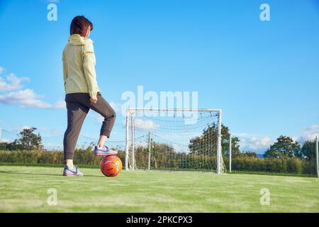 Une joueuse de football tient une balle de football avec son pied Banque D'Images