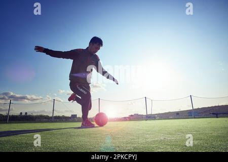 Un joueur qui essaie de donner un coup de pied au ballon Banque D'Images