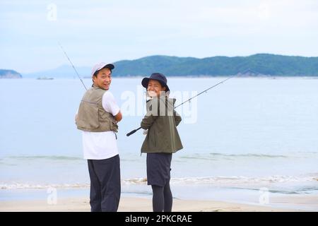 Hommes et femmes pêchant sur la plage Banque D'Images