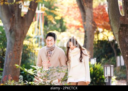 Un couple dans leur 20s promenade le long d'une avenue bordée d'arbres à la fin de l'automne Banque D'Images