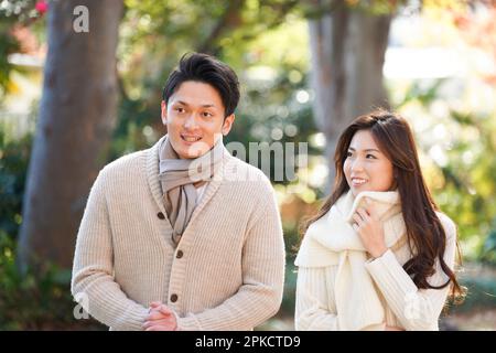 Un couple dans leur 20s promenade le long d'une avenue bordée d'arbres à la fin de l'automne Banque D'Images