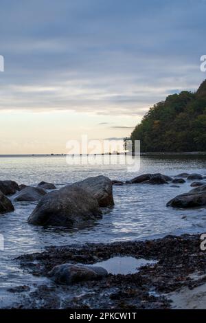 Une soirée sereine sur la côte rocheuse de Rügen, Allemagne. Les rochers sont assis dans la paisible mer Baltique au crépuscule, créant une scène paisible et sombre. Banque D'Images