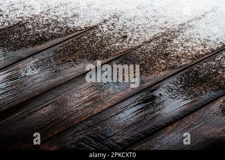 La neige fond sur le plancher de bois de la véranda ouverte d'une maison privée. Banque D'Images