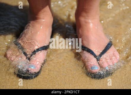 Photo de dossier datée du 12/06/2014 de pieds en tongs sur la plage de Praia da Luz, Portugal. On estime que deux millions de vacanciers britanniques se dirigent à l'étranger pendant le week-end des vacances de Pâques. L'organisation de voyages ABTA, qui a calculé le chiffre, a déclaré qu'il y a une forte demande de voyages en Espagne continentale, les îles Canaries et Baléares, l'Algarve, Madère, Chypre, Croatie, Italie, Grèce et sud de la Turquie. Selon les chiffres de la société d'analyse aéronautique Cirium, 10 218 vols devraient quitter les aéroports britanniques entre le vendredi Saint et le lundi de Pâques. Date de publication : vendredi 7 avril 2023. Banque D'Images