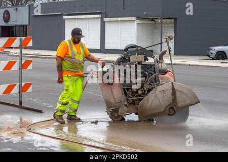 Detroit, Michigan, Un travailleur exploite une scie à béton à l'état de marche dans le cadre d'un projet visant à créer des pistes cyclables protégées, des trottoirs plus larges et à planter Banque D'Images