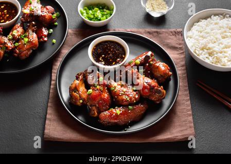 Ailes de poulet au miel et au soja sur une assiette sur fond de pierre sombre. Vue rapprochée Banque D'Images