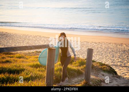 Femme marchant sur la plage avec une planche de surf Banque D'Images