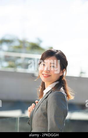 Femme en costume regardant en arrière et souriant Banque D'Images