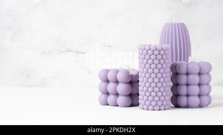 Cire d'olive faite à la main différentes formes lilas, violet bougie sur une table en marbre blanc à la maison. Bougie végétalienne durable, matériaux naturels. Banque D'Images