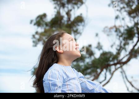 Une demi-fille riant devant l'arbre Banque D'Images