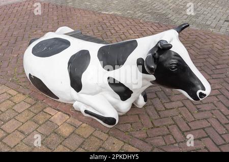 vache en plastique avec des taches noires et blanches debout à l'extérieur de la rue Banque D'Images