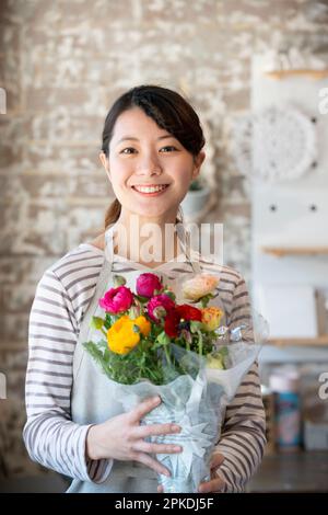 Femme de shopping souriante tenant un bouquet de fleurs Banque D'Images